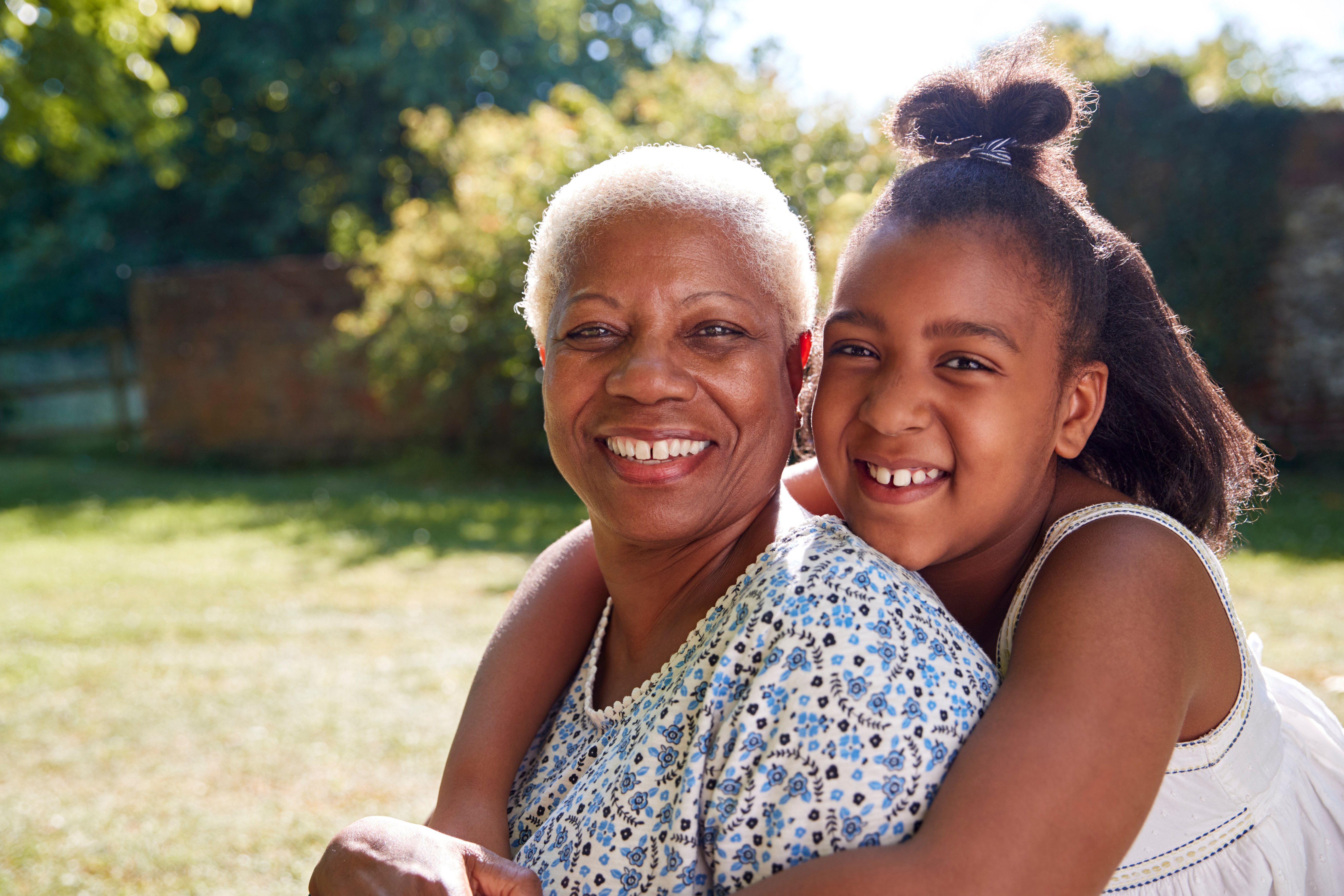 senior-black-woman-and-granddaughter-sit-embracing-9D84B3K